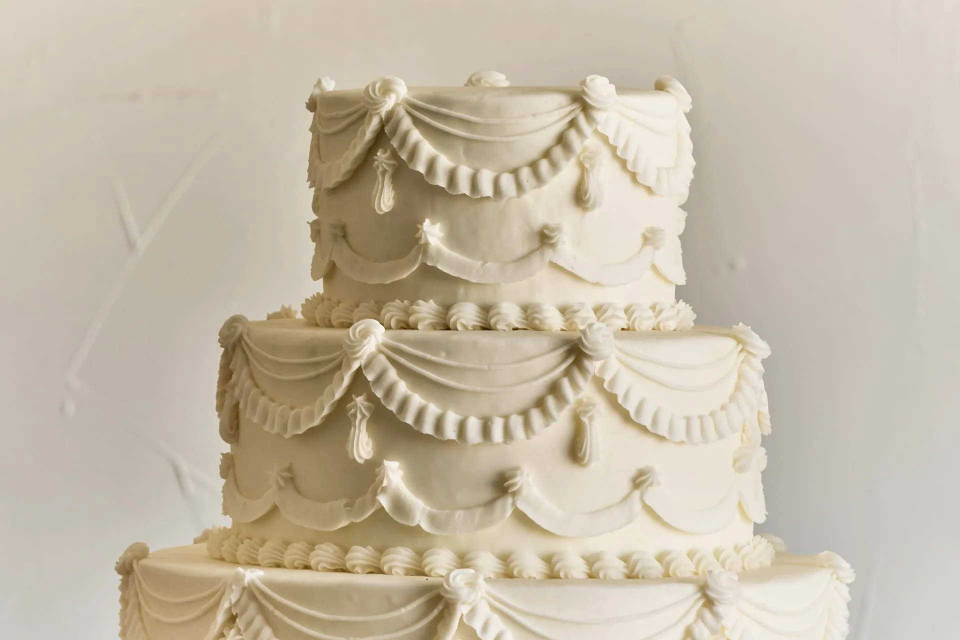 Classic three-tier wedding cake with traditional white buttercream and elegant draping